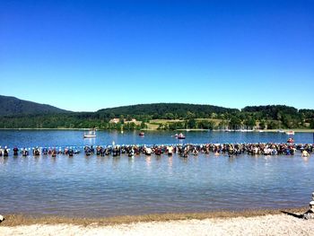 View of swimmers in lake against blue sky