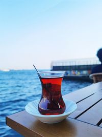 Close-up of drink on table against sea