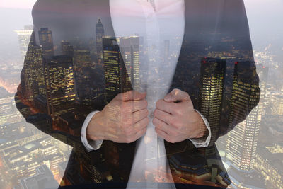 Digital composite image of man holding glass cityscape