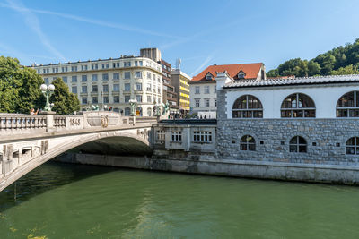 Bridge over river by buildings against sky in city