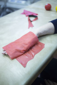 Cropped hand of patient wrapped in red adhesive bandage on hospital bed