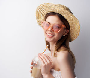 Portrait of smiling young woman wearing hat against white background