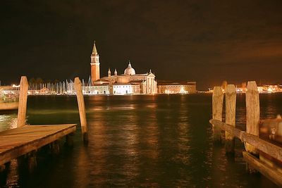 View of illuminated castle by river against sky