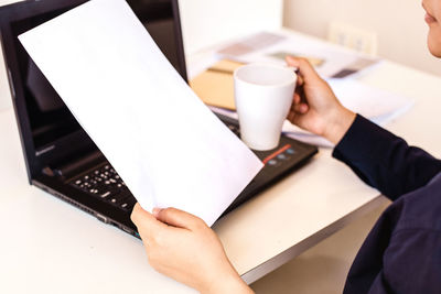 Midsection of man holding coffee cup on table