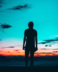 Silhouette of woman standing against sky at sunset