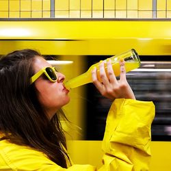 Woman drinking juice against yellow light trail