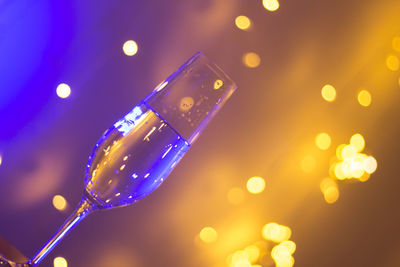 Close-up of champagne flute against illuminated lights