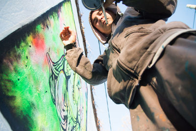 Low angle view of street artist painting wall