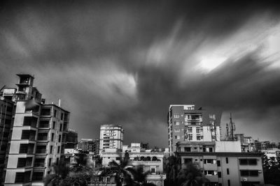 Buildings in city against storm clouds