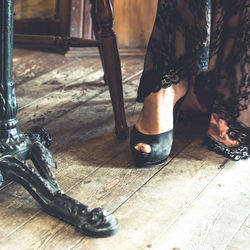 Low section of woman by table on floorboard