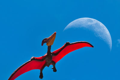 Low angle view of kites flying against clear blue sky