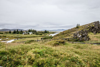 Scenic view of green landscape and sea against sky