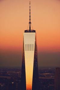 One world trade center in city against orange sky