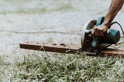 Cropped hands of carpenter using circular saw on wood