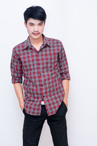 Portrait of young man standing against white background