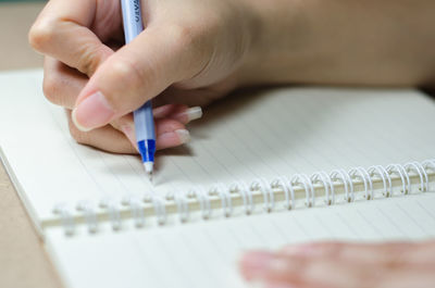 Close-up of hand holding pen on table