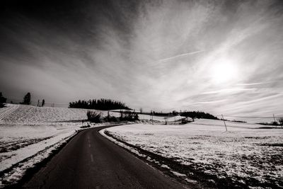 Road amidst snow covered landscape against sky