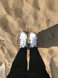 Low section of person standing on sand