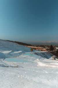 Scenic view of snow covered landscape against clear blue sky