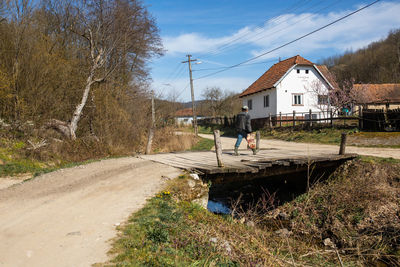 Man by road amidst buildings against sky