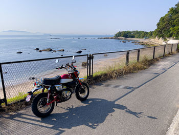 Bicycles on road by sea against clear sky