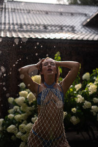 Young woman in bikini standing in the garden in the rain