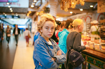 Portrait of young woman standing in illuminated market