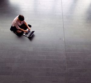 High angle view of woman using laptop while sitting on floor