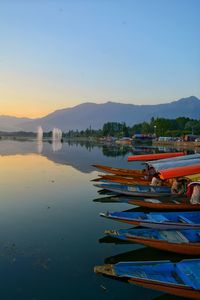 Boats moored in lake against sky during sunset