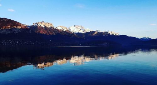 Scenic view of lake and mountains against blue sky