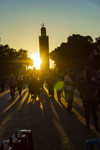 People on street in city against sky during sunset