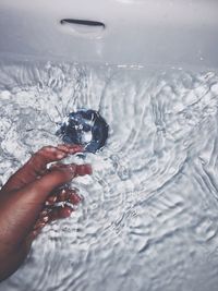 High angle view of human hand in bathroom sink