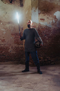 Brave viking warrior with beard in chain mail and flaming sword stands in ancient mysterious castle.