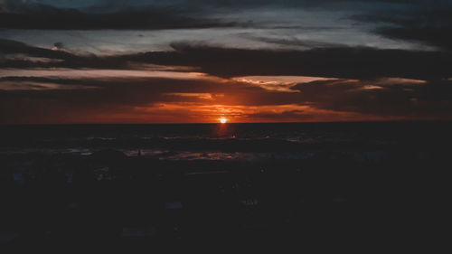 Scenic view of sea against dramatic sky during sunset