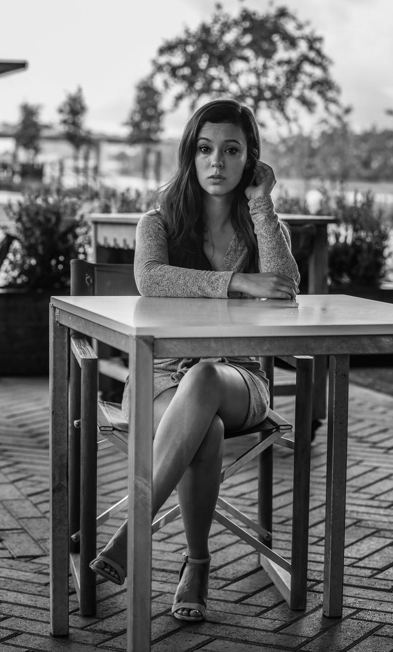 one person, young adult, sitting, seat, young women, real people, portrait, front view, looking at camera, full length, lifestyles, chair, leisure activity, women, beautiful woman, focus on foreground, casual clothing, long hair, hairstyle, outdoors, contemplation