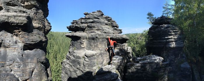 Man standing on rock against sky