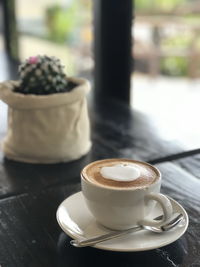 Coffee cup on table with blurred cactus as a background