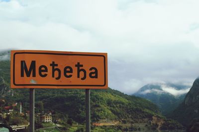 Road sign against cloudy sky