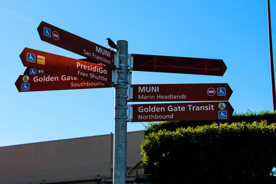 Low angle view of information signs against clear blue sky