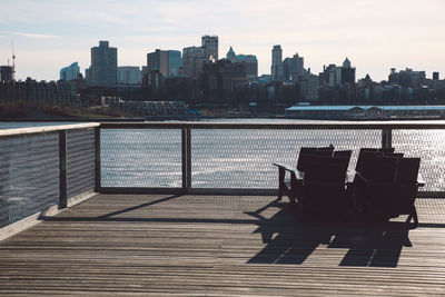 Lounge chairs on promenade against manhattan skyline on sunny day