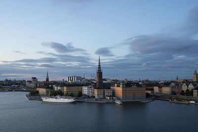 Buildings at waterfront against cloudy sky
