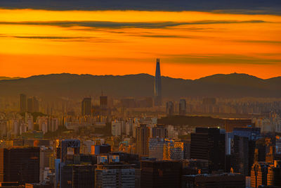 Buildings in city against orange sky