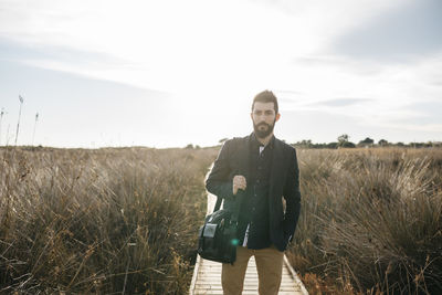 Mid adult man walking on boardwalk against sky