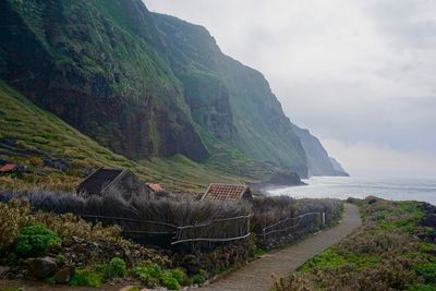 Scenic view of sea by mountains against sky