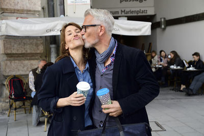 Mature couple with reusable bamboo cups kissing in the city