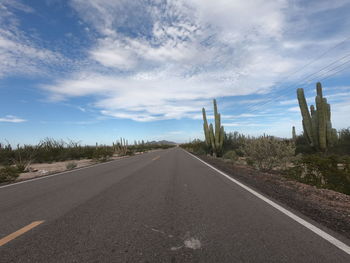 Empty road by city against sky