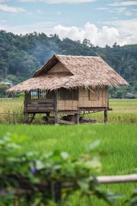 Stilt house on land against sky