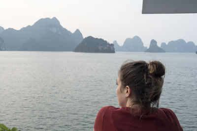 Rear view of woman looking at sea against mountains