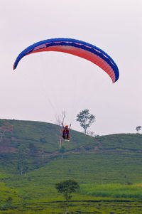 Low angle view of person paragliding against clear sky