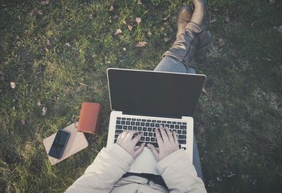 Low section of woman using mobile phone in grass